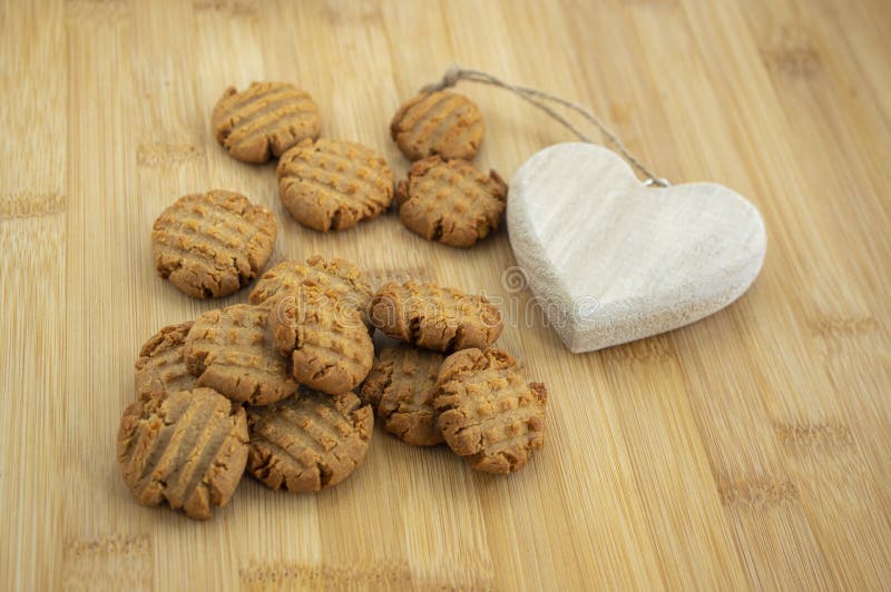 Very tasty peanut butter biscuits on bamboo wooden board with decorative wood heart, golden baked healthy