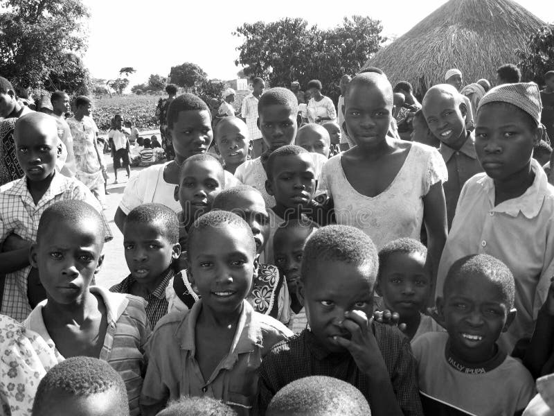 Verzamelen komen de menigte Afrikaanse nieuwsgierige kinderen die zich als arbeiders van de hulphulp aan stock foto Verzamelen komen de menigte Afrikaanse nieuwsgierige kinderen die zich als arbeiders van de hulphulp aan stock foto
