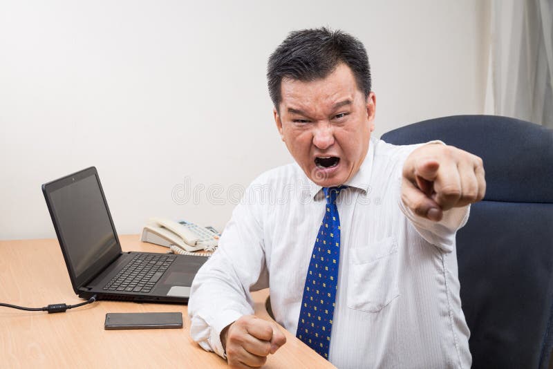 Verärgerter und stressiger asiatischer Manager, der in offic schreit und zeigt stockfotografie Verärgerter und stressiger asiatischer Manager, der in offic schreit und zeigt stockfotografie