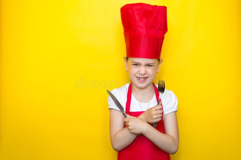 Verärgertes Mädchen im Klagen-Holdinglöffel eines roten Chefs und in der Gabel, Arme kreuzte, auf gelbem Hintergrund mit Kopienra lizenzfreie stockfotos Verärgertes Mädchen im Klagen-Holdinglöffel eines roten Chefs und in der Gabel, Arme kreuzte, auf gelbem Hintergrund mit Kopienra lizenzfreie stockfotos