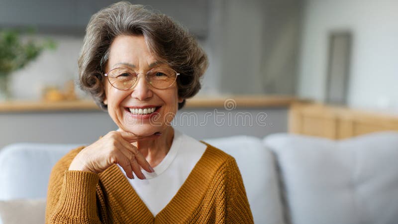 Vesel în vârstă bunicuță odihnindu-se la domiciliu uita-te și zâmbind la camera fericit mai în vârstă greyhaired doamnă sitting pe royalty free stock images