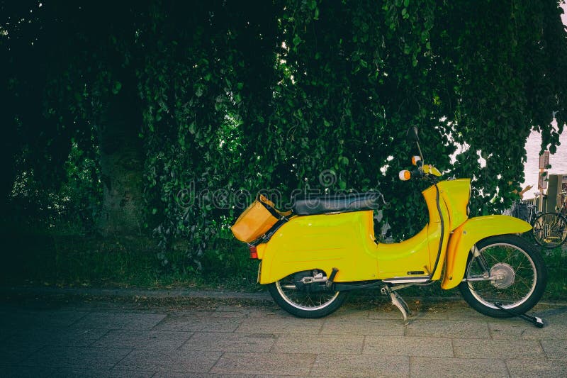 Vespa gialla d'annata che parcheggia il motorino progettato italiano iconico fotografie stock libere da diritti Vespa gialla d'annata che parcheggia il motorino progettato italiano iconico fotografie stock libere da diritti