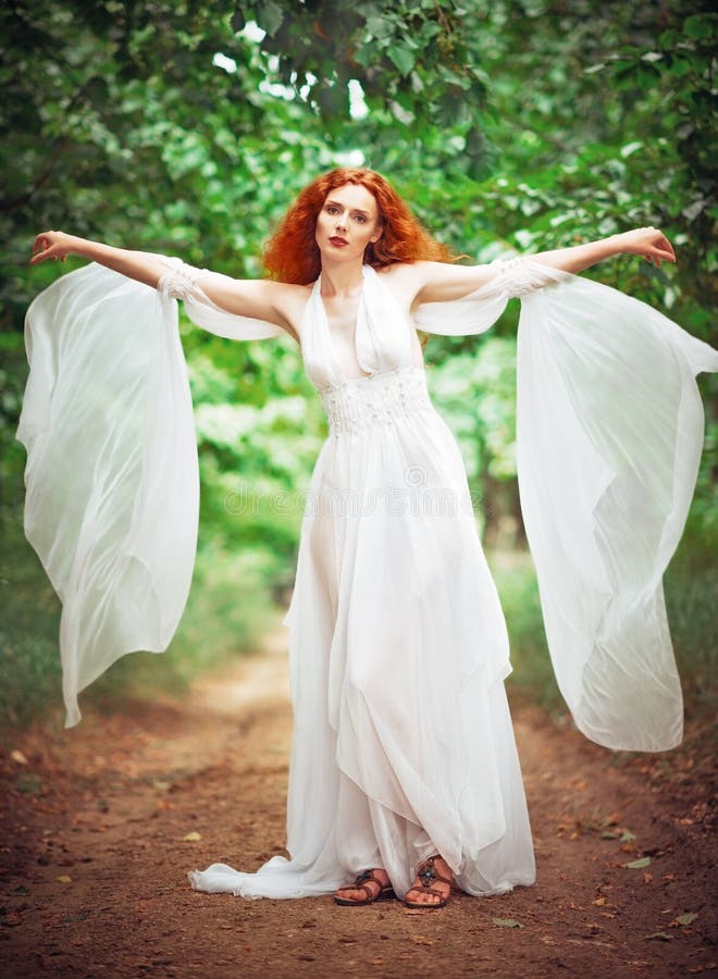 Vestido branco vestindo da mulher bonita do ruivo em um jardim imagem de stock Vestido branco vestindo da mulher bonita do ruivo em um jardim imagem de stock