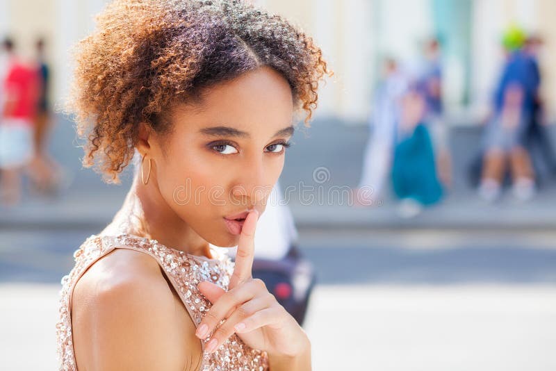 Vestido vestindo afro-americano da menina ou da jovem mulher com seu dedo em seus bordos que pedem o silêncio ou que mantêm um se fotos de stock royalty free Vestido vestindo afro-americano da menina ou da jovem mulher com seu dedo em seus bordos que pedem o silêncio ou que mantêm um se fotos de stock royalty free