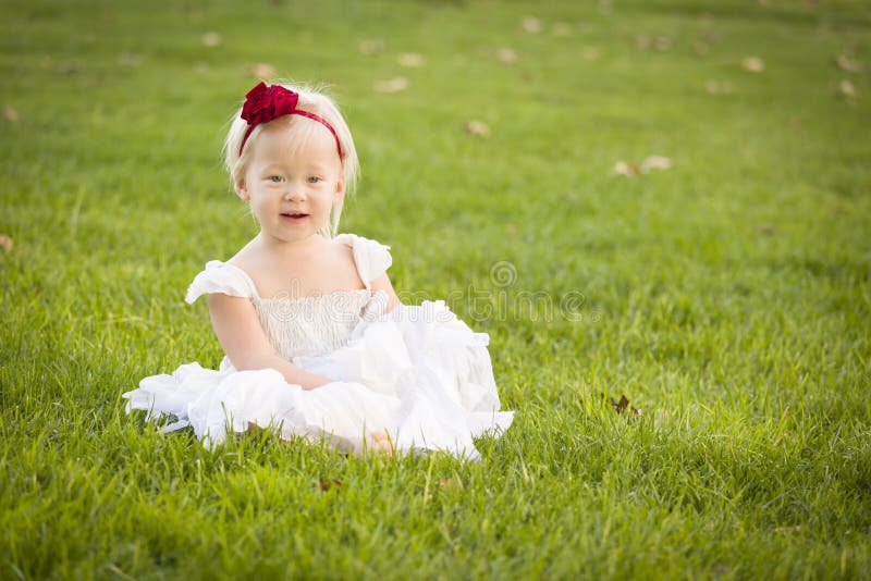Vestito bianco d'uso dalla bambina adorabile in un campo di erba fotografie stock Vestito bianco d'uso dalla bambina adorabile in un campo di erba fotografie stock