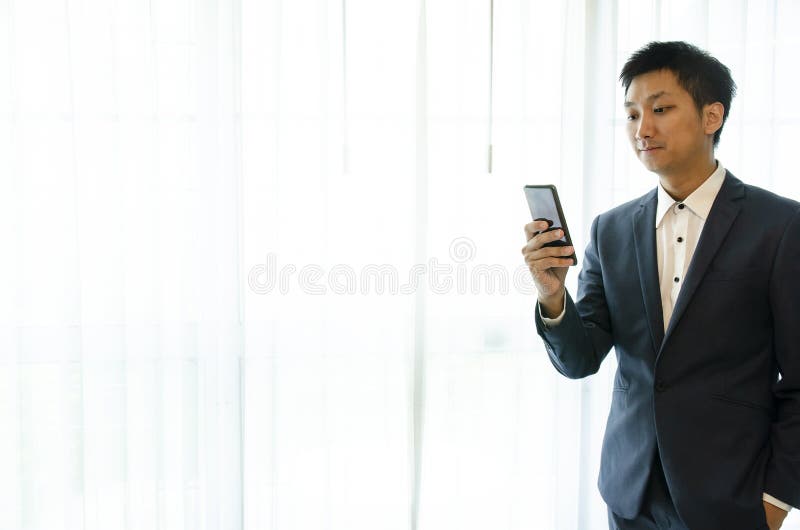 Vestito d'uso dell'uomo di affari, guardante smartphone Ufficio del sottotetto dello spazio aperto Fondo panoramico delle finestr immagine stock Vestito d'uso dell'uomo di affari, guardante smartphone Ufficio del sottotetto dello spazio aperto Fondo panoramico delle finestr immagine stock