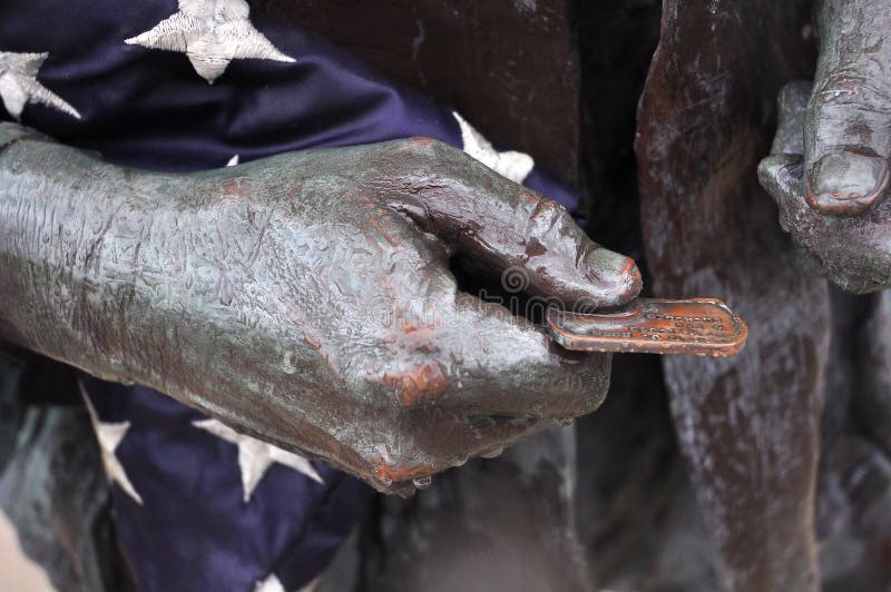 Veteran holding dogtag and flag at Vietnam war memorial stock image Veteran holding dogtag and flag at Vietnam war memorial stock image