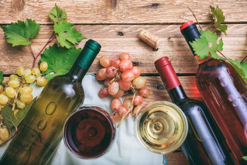Vetri e bottiglie di vino rosso e bianco su fondo di legno, spazio della copia Uva e foglie fresche dell'uva come decorazione immagini stock libere da diritti Vetri e bottiglie di vino rosso e bianco su fondo di legno, spazio della copia Uva e foglie fresche dell'uva come decorazione immagini stock libere da diritti