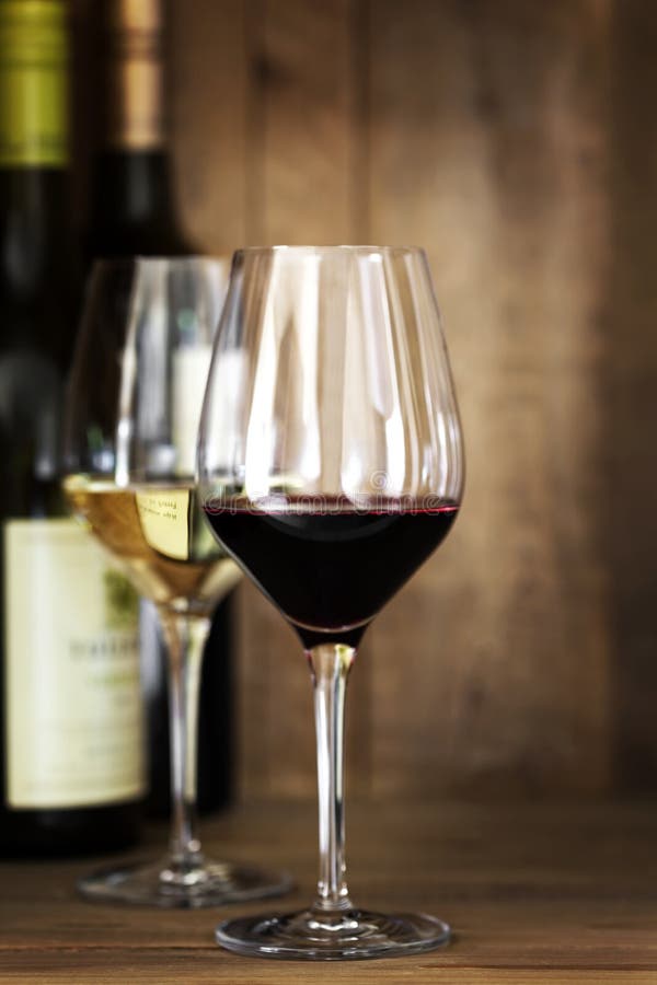 Vetri e bottiglie di vino rosso e bianco sopra la quercia fotografia stock