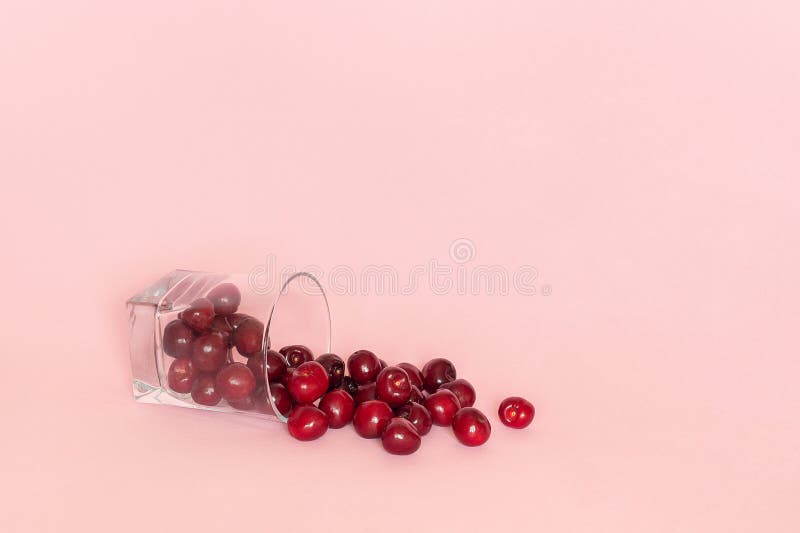 Vetro caduto con la ciliegia matura rossa sparsa su fondo rosa Concetto di succo naturale fresco, frullati, cibo sano o fotografia stock libera da diritti Vetro caduto con la ciliegia matura rossa sparsa su fondo rosa Concetto di succo naturale fresco, frullati, cibo sano o fotografia stock libera da diritti