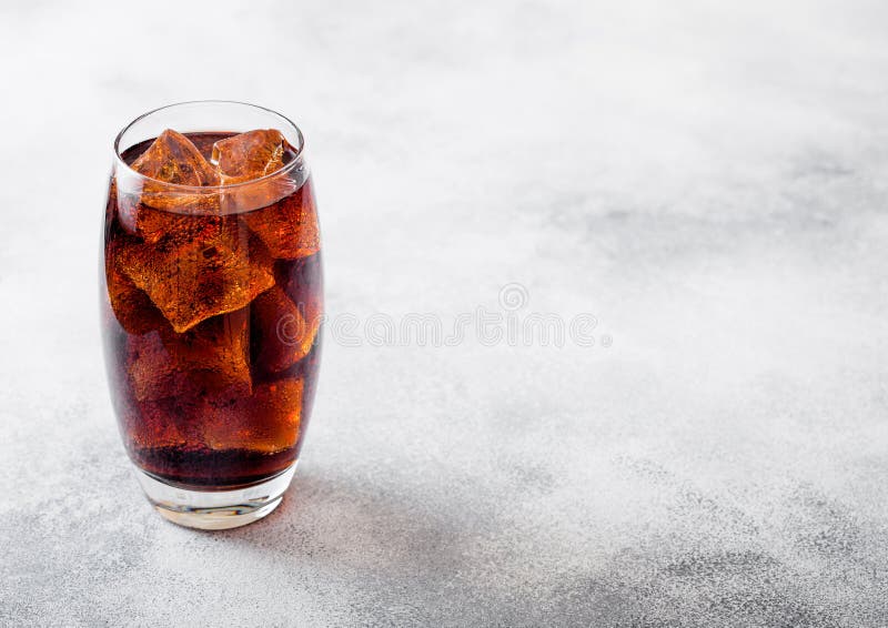Vetro della bevanda della soda della cola con i cubetti di ghiaccio e le bolle sul fondo di pietra del tavolo da cucina fotografia stock Vetro della bevanda della soda della cola con i cubetti di ghiaccio e le bolle sul fondo di pietra del tavolo da cucina fotografia stock