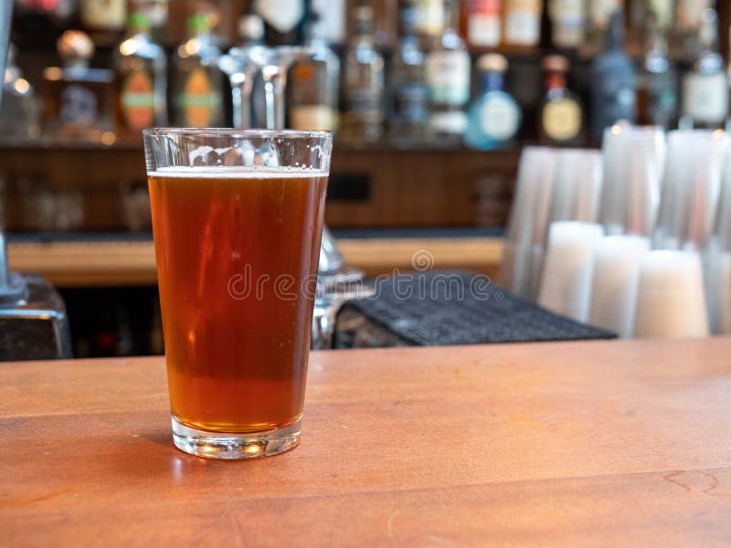 Vetro della pinta di birra che si siede sul contatore della barra nel tempo di giorno immagini stock libere da diritti Vetro della pinta di birra che si siede sul contatore della barra nel tempo di giorno immagini stock libere da diritti