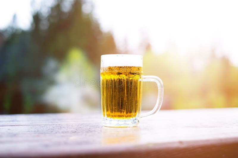 Vetro di birra leggera con schiuma su una tavola di legno Ricevimento all'aperto Sfondo naturale alcool Birra alla spina fotografia stock Vetro di birra leggera con schiuma su una tavola di legno Ricevimento all'aperto Sfondo naturale alcool Birra alla spina fotografia stock