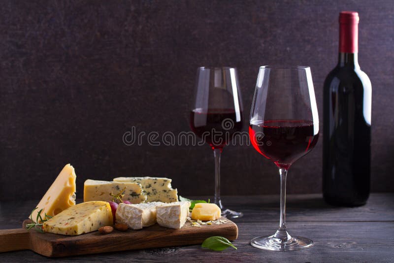 Vetro e bottiglia di vino con formaggio, l'uva ed i dadi sulla tavola di legno nera Vino ed alimento immagini stock libere da diritti