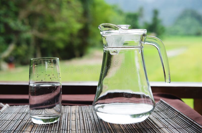 Vetro e lanciatore di acqua sulla tavola immagine stock libera da diritti Vetro e lanciatore di acqua sulla tavola immagine stock libera da diritti