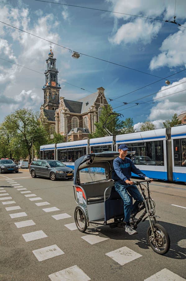 Via con cielo blu, la vecchia chiesa, la gente, il ciclista ed il tram passanti vicino a Amsterdam fotografia stock libera da diritti