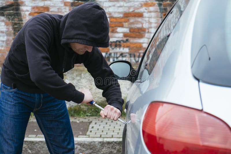 A robber trying to steal a car in a street. A robber trying to steal a car in a street