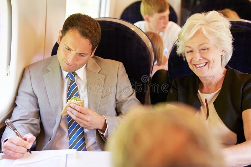 Viagem de trem de Eating Sandwich On do homem de negócios fotografia de stock royalty free Viagem de trem de Eating Sandwich On do homem de negócios fotografia de stock royalty free