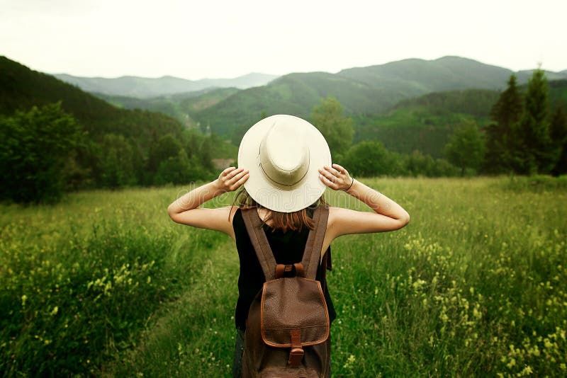 Viaggiatore della donna con il cappello della tenuta dello zaino ed esaminare stupente immagine stock libera da diritti Viaggiatore della donna con il cappello della tenuta dello zaino ed esaminare stupente immagine stock libera da diritti