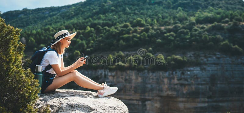 Viaggiatore di cappelli e zaino che si arrampica in natura e usa internet su una ragazza turista dello smartphone che chiacchiera