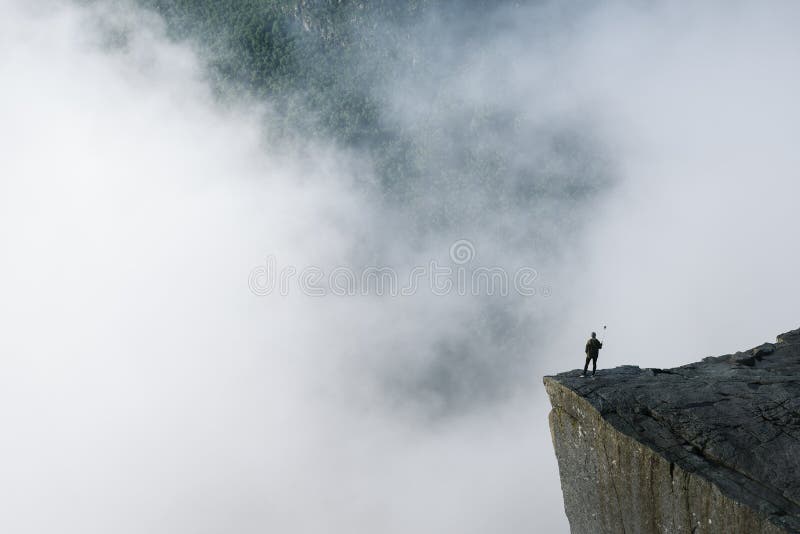 Viaggiatore sulla roccia Preikestolen, Norvegia fotografia stock Viaggiatore sulla roccia Preikestolen, Norvegia fotografia stock