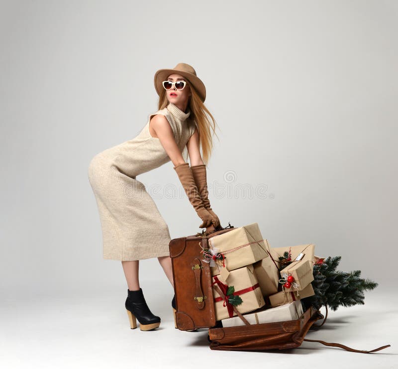 Viajante bonito da mulher no chapéu com o saco retro de couro aberto grande completo de presentes do presente de Natal fotografia de stock royalty free Viajante bonito da mulher no chapéu com o saco retro de couro aberto grande completo de presentes do presente de Natal fotografia de stock royalty free