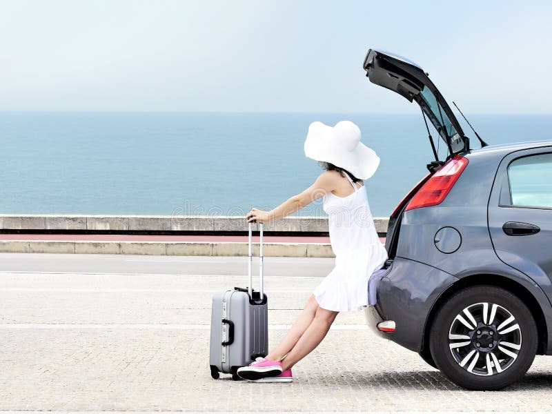 Viajante da mulher que senta-se no carro do carro com porta traseira fotografia de stock Viajante da mulher que senta-se no carro do carro com porta traseira fotografia de stock