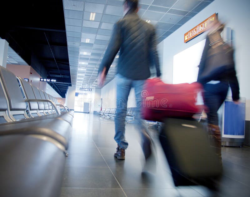 Airport scene with people carrying luggage in the airport departure gate preparing to travel by plane. Airport scene with people carrying luggage in the airport departure gate preparing to travel by plane