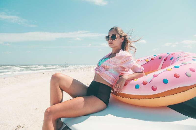 Girl relaxing on donut lilo on the beach. Playing with inflatable ring. Car trip to summer holiday idyllic. Girl relaxing on donut lilo on the beach. Playing with inflatable ring. Car trip to summer holiday idyllic