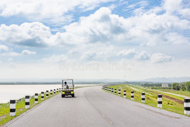Viaje escénico del camino del paisaje en la carretera vacía y el carro de golf eléctrico imagenes de archivo Viaje escénico del camino del paisaje en la carretera vacía y el carro de golf eléctrico imagenes de archivo