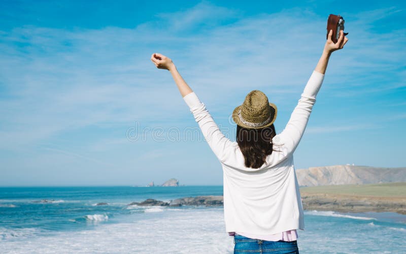 Hipster woman enjoy freedom on vacation travel. Successful funky girl raising arms towards the sea in Asturias coast, Spain. Hipster woman enjoy freedom on vacation travel. Successful funky girl raising arms towards the sea in Asturias coast, Spain.