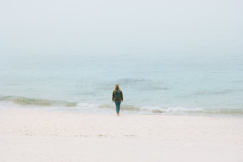 Viajero de la mujer que camina solamente en la playa de niebla del océano fotografía de archivo Viajero de la mujer que camina solamente en la playa de niebla del océano fotografía de archivo