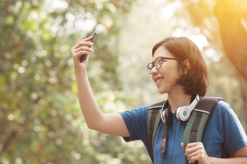 Viandante asiatica della donna di vetro con lo zaino che prende la foto della natura con fotografia stock Viandante asiatica della donna di vetro con lo zaino che prende la foto della natura con fotografia stock