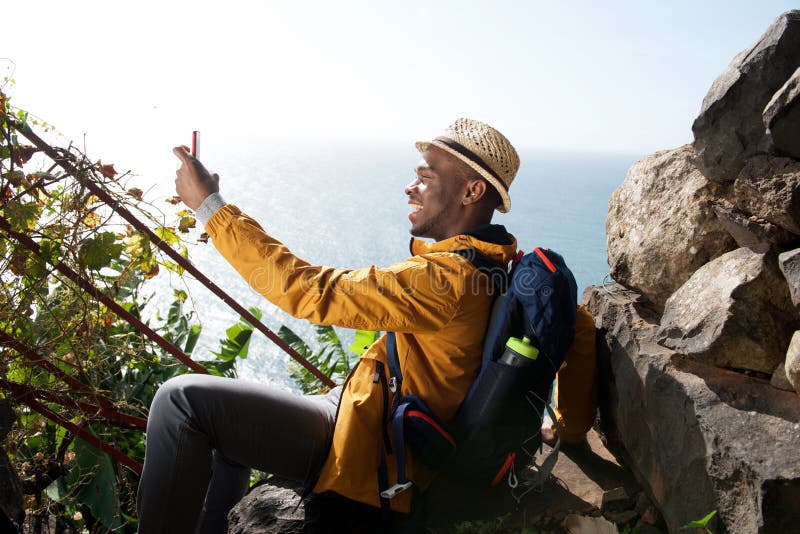 Viandante maschio afroamericana felice che si rilassa e che prende selfie fotografia stock libera da diritti Viandante maschio afroamericana felice che si rilassa e che prende selfie fotografia stock libera da diritti