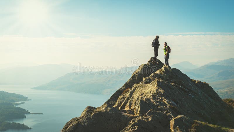 Viandanti femminili sopra la montagna che prende una rottura e che gode di una vista della valle immagini stock Viandanti femminili sopra la montagna che prende una rottura e che gode di una vista della valle immagini stock