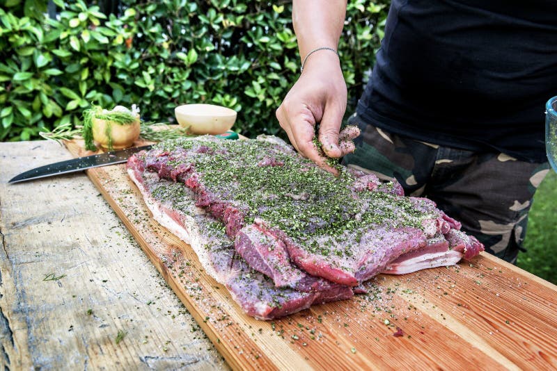 Viande de assaisonnement de boucher avec du sel et des herbes pour roulé vers le haut du porc photo libre de droits Viande de assaisonnement de boucher avec du sel et des herbes pour roulé vers le haut du porc photo libre de droits