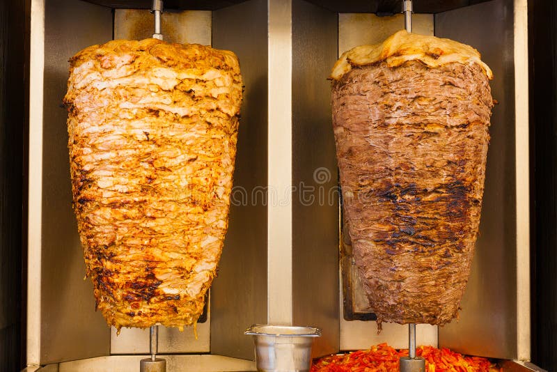 Delicious slabs of skewered fast food shawerma chicken and lamb meat turn side by side on a spit. This is common sandwich meat found in fast food in the Middle East. Delicious slabs of skewered fast food shawerma chicken and lamb meat turn side by side on a spit. This is common sandwich meat found in fast food in the Middle East.