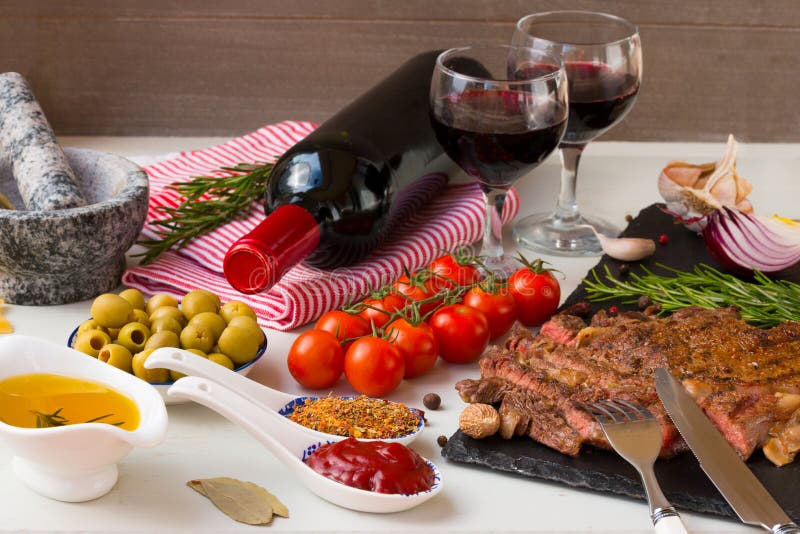 Viande grillée fraîche Rôti moyen grillé d'entrecôte de boeuf sur le conseil en pierre noir, le vin rouge et deux pleins verres d image libre de droits Viande grillée fraîche Rôti moyen grillé d'entrecôte de boeuf sur le conseil en pierre noir, le vin rouge et deux pleins verres d image libre de droits