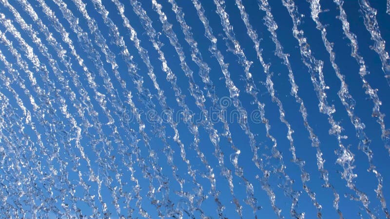 Vibrant display of water streams against a bright blue sky, creating a dynamic, abstract pattern ideal for nature or stock video footage