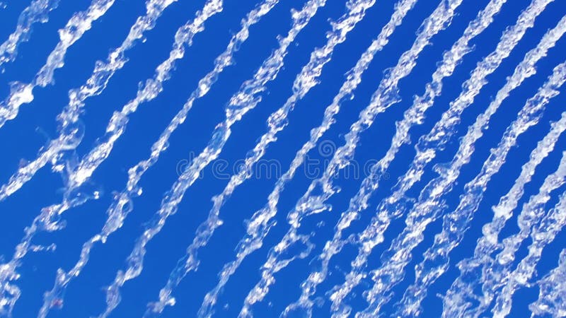 Vibrant display of water streams against a bright blue sky, creating a dynamic, abstract pattern ideal for nature or stock video footage
