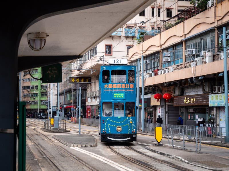 Vibrante elétrico azul viaja ao longo de uma movimentada rua em Hong Kong cercada por lojas e edifícios fotografia de stock