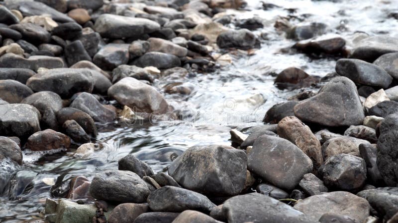 Vicino al fiume che scorre lungo le pietre grigie Riprese in borsa Brook rapidi e freddi con flusso d'acqua chiaro fotografia stock libera da diritti Vicino al fiume che scorre lungo le pietre grigie Riprese in borsa Brook rapidi e freddi con flusso d'acqua chiaro fotografia stock libera da diritti