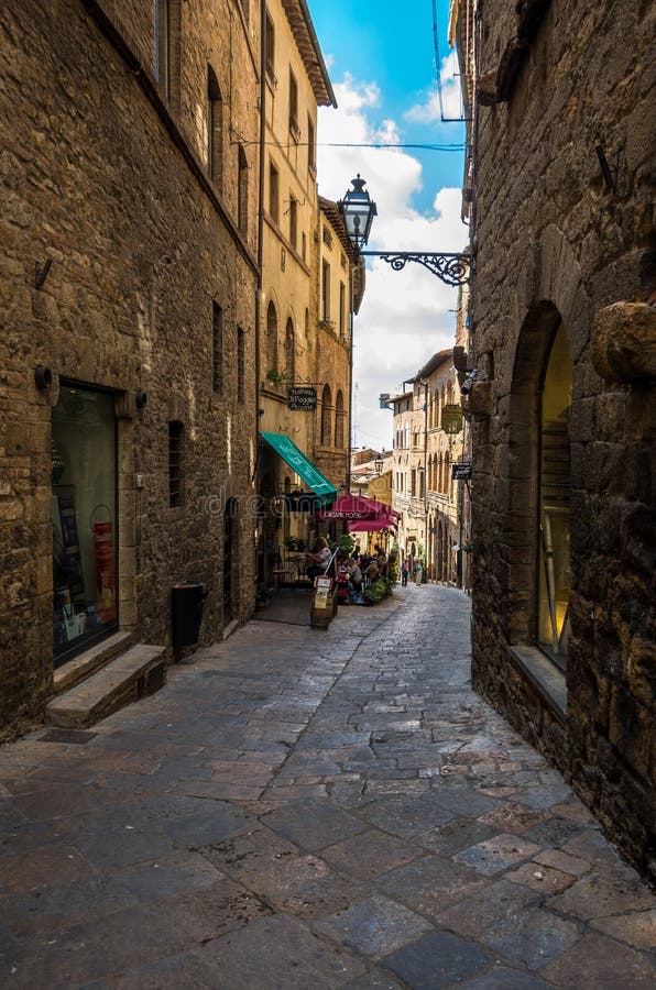 Vicolo stretto facente un giro turistico nel vecchio centro urbano di Voltera, Italia immagine stock Vicolo stretto facente un giro turistico nel vecchio centro urbano di Voltera, Italia immagine stock