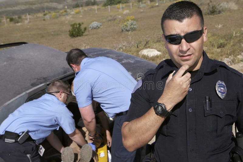 Victime d'accident de voiture de With Paramedics Rescuing de policier image stock Victime d'accident de voiture de With Paramedics Rescuing de policier image stock