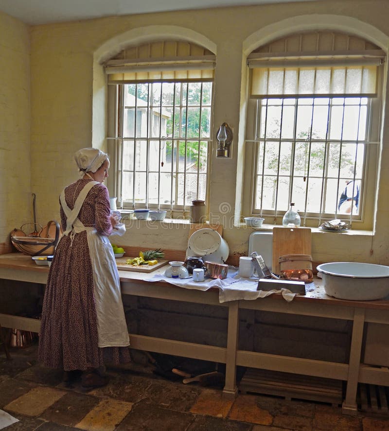 Victorian Kitchen maid preparing food by window.