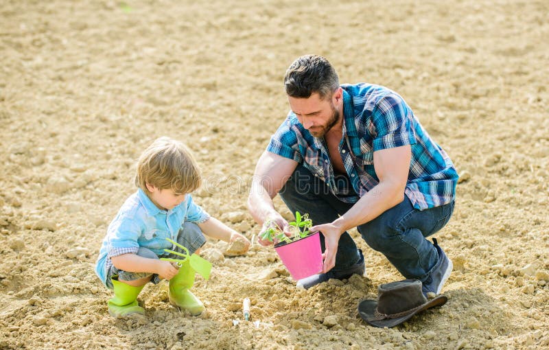 New life. soils and fertilizers. father and son planting flowers in ground. rich natural soil. Eco farm. earth day. earth day. Family tree. small boy child help father in farming. Gifts of nature. New life. soils and fertilizers. father and son planting flowers in ground. rich natural soil. Eco farm. earth day. earth day. Family tree. small boy child help father in farming. Gifts of nature.