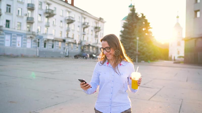 4 in 1 video Man en vrouw die op smartphone en het drinken sap spreken die onderaan de straat, langzame motie lopen