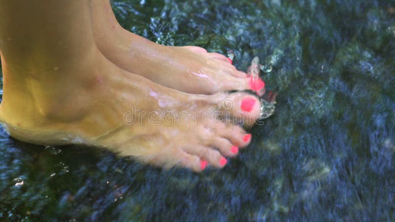 Video van een naakte voetenvrouw die en haar benen in het water in een rivier met een snelle stroom bespatten schoppen