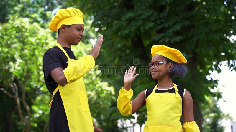 4.000 video zwart afrika koelt kinderen in gele chef-koks hoed en apron clap elkaars handen en geeft vijf. zwarte afrika