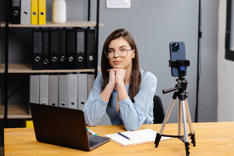 Videoconference And Training. Class of diverse students learning remotely online using web app. Female teacher providing lesson with laptop, recording video on cellphone on tripod